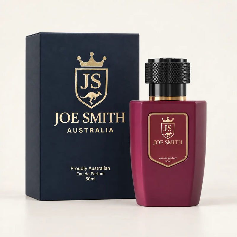 Joe Smith 50 ml burgundy perfume bottle with black cap beside its navy presentation box